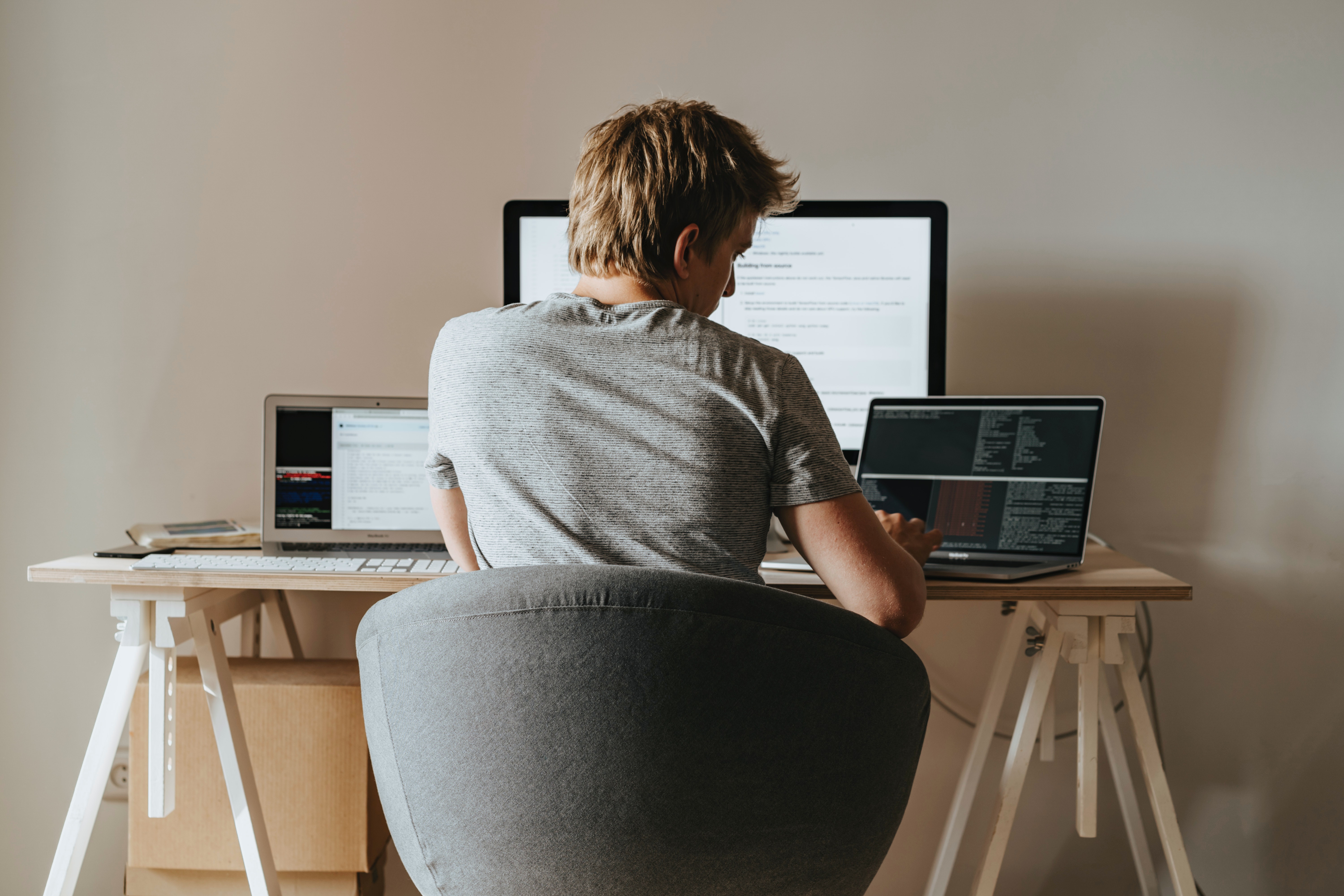 Man-Sitting-at-Desk-with-back-Facing-Camera-and-Computer-Screens