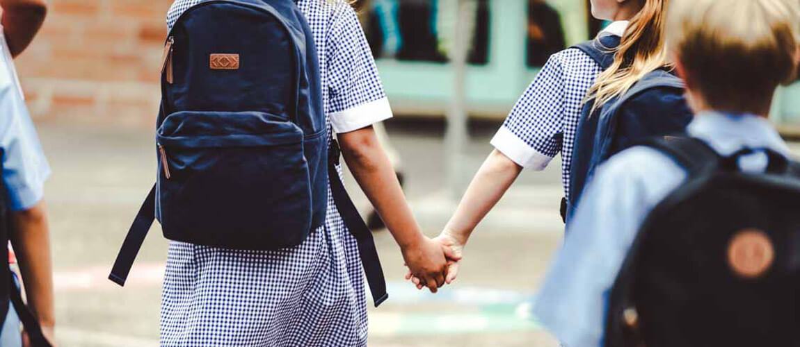 School children wearing uniforms and carrying backpacks.